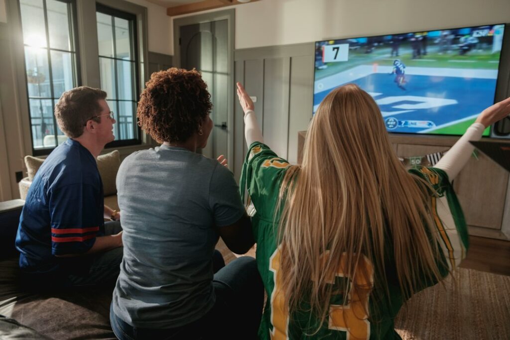 Friends watching an American football game on a 4K television while checking stream quality