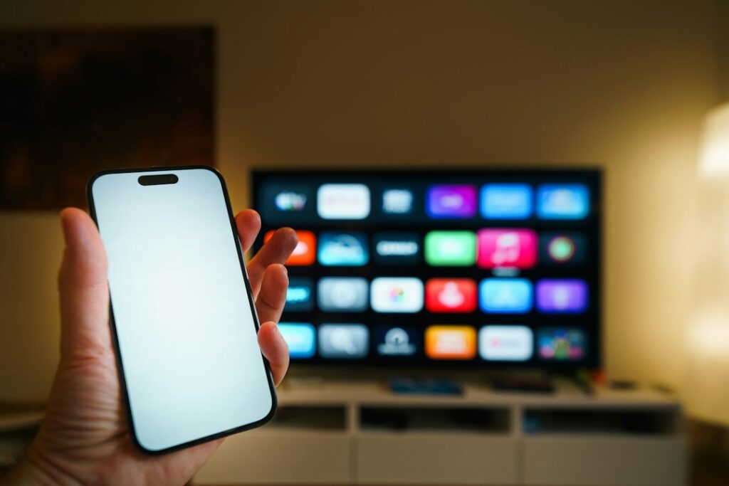 Smartphone held in front of a smart TV illustrating Apple TV and Android TV player choices