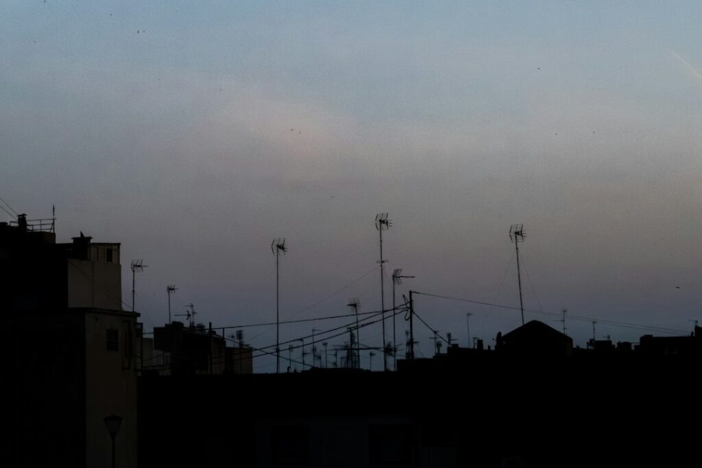 Rooftop television antennas at dusk, illustrating over-the-air local TV reception